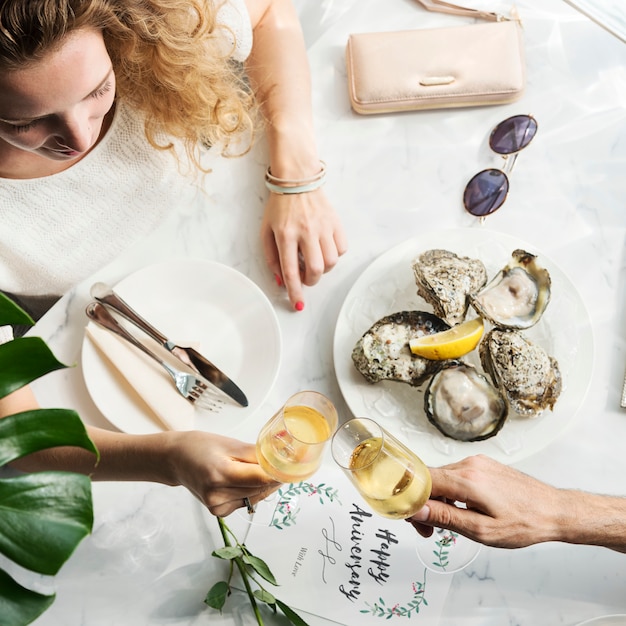 Um casal em um encontro levantar taças de champanhe e ter ostras frescas