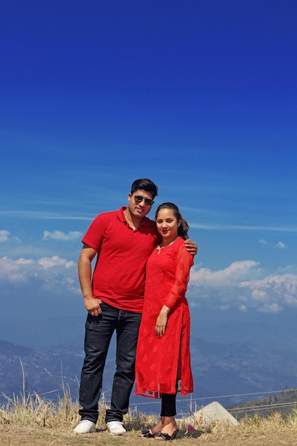 Foto um casal em um vestido vermelho está na frente de um céu azul.