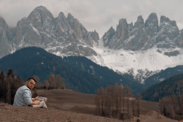 Um casal está sentado em uma colina em frente às montanhas