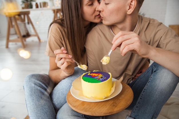 um casal está sentado no chão comendo bolo de bento com a inscrição amor é abraços e beijos