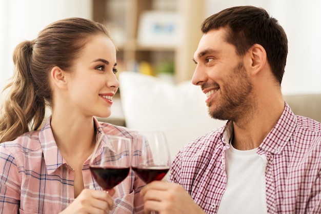 Um casal feliz a beber vinho vermelho em casa.