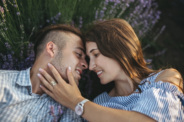 Um casal feliz beijando ao pôr do sol no campo de lavanda.