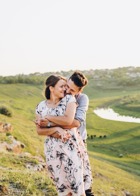 Um casal feliz beijando e se divertindo ao pôr do sol no campo