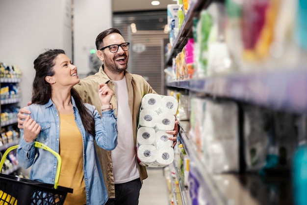 Um casal feliz comprando papel higiênico no supermercado