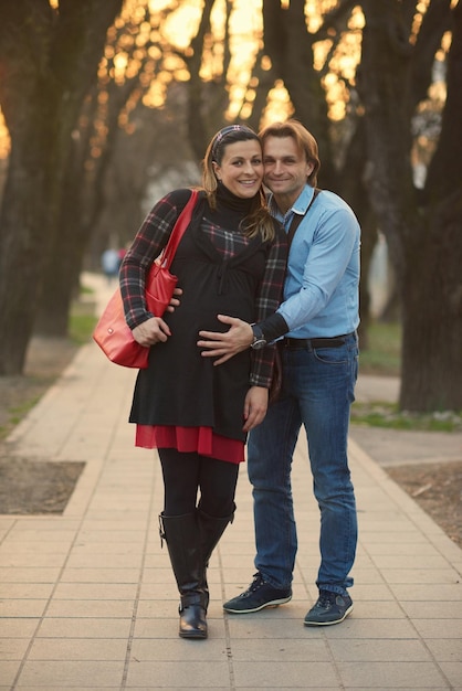 Um casal feliz e jovem grávida diverte-se e relaxa ao ar livre.