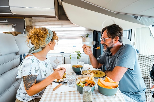 Foto um casal feliz passando tempo juntos se divertindo durante o almoço dentro de um camper pessoas com campistas sorrindo pensando no novo destino homem e mulher comendo em paz