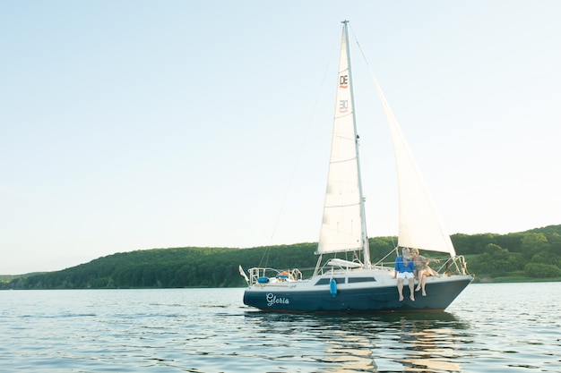 Um casal feliz sênior navegando e sentado ao volante de um barco a vela no lago.