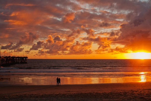 Um casal fica na praia no belo pôr do sol perto do Oceano Pacífico Califórnia