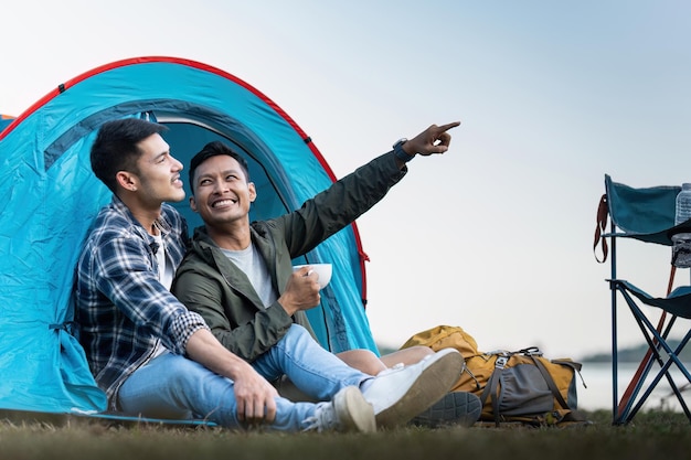 Um casal gay asiático feliz a acampar juntos numa floresta numa viagem romântica de vocação.