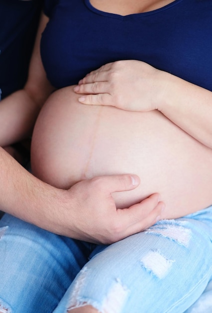 Um casal grávida abraça uma mulher com um close do estômago Close de um casal humano segurando uma barriga grávida em suas mãos O marido abraça gentilmente sua esposa grávida