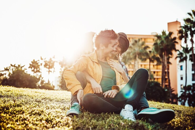 Foto um casal homossexual feliz sentado na grama durante o pôr-do-sol