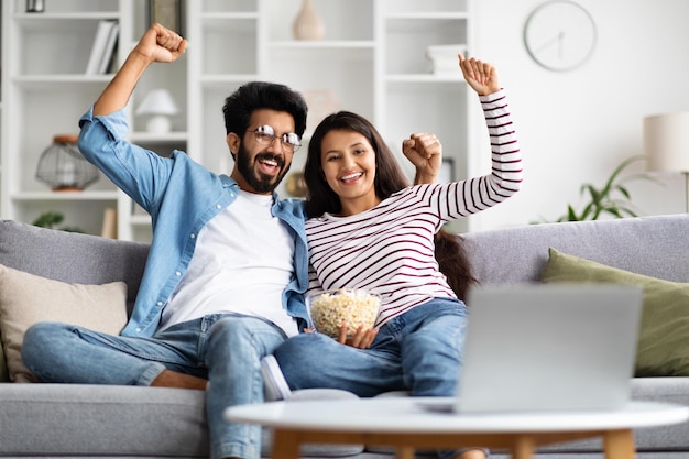 Um casal indiano entusiasmado a ver um jogo de futebol em casa.