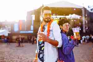 Foto um casal jovem e alegre num festival de música, amigos felizes a beber cerveja e a divertir-se.