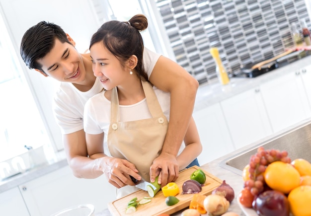 Um casal jovem olhando um para o outro enquanto cortam abobrinha juntos na cozinha