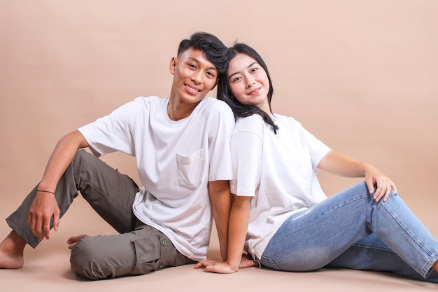 Um casal jovem sentado no chão vestindo uma camiseta branca em branco