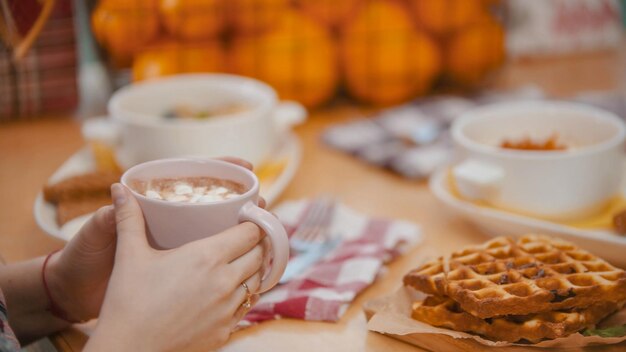 Um casal no restaurante tomando um café da manhã de waffles e panquecas bebendo um café com marshmallows