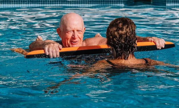 Um casal octogenário com muito bom aspecto físico usufrui da piscina durante o verão Situação descontraída