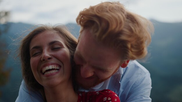 Um casal se abraçando e sorrindo com montanhas ao fundo