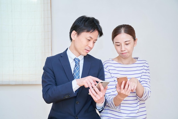 Um casal se consultando enquanto olha para a tela de um smartphone