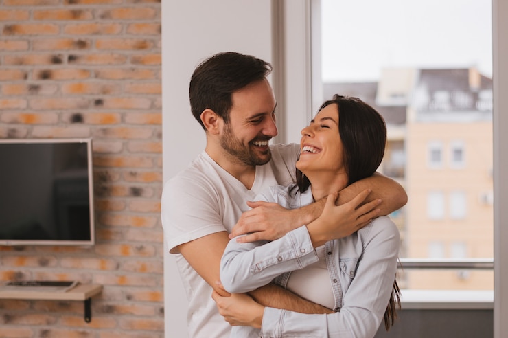 Um casal se divertindo muito perto da janela