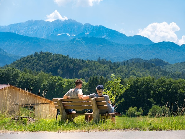 Um casal se senta em um banco e desfruta de uma bela vista dos Alpes