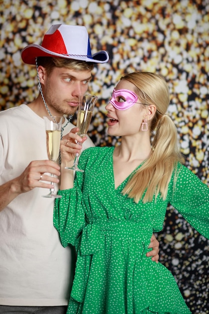 Um casal usando máscaras de carnaval e segurando taças de champanhe