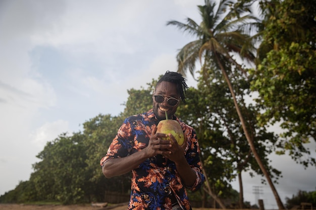 Um cavalheiro sorri enquanto desfruta de leite de coco do coco que ele está segurando