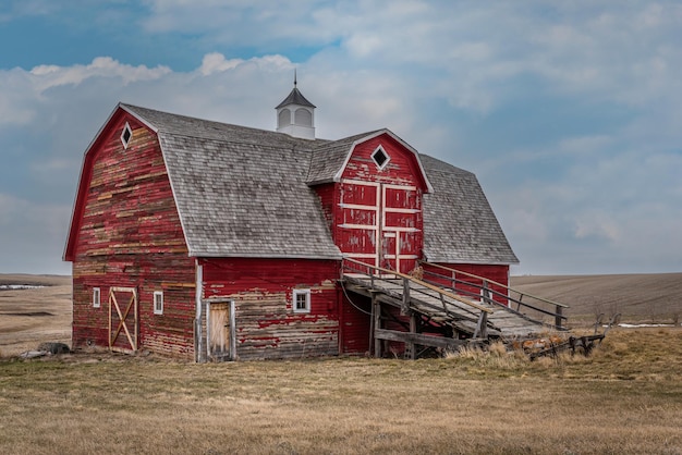 Foto um celeiro vermelho abandonado com uma rampa de carroça nas pradarias em saskatchewan, canadá