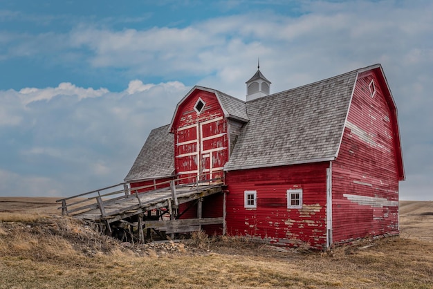 Foto um celeiro vermelho abandonado com uma rampa de carroça nas pradarias em saskatchewan, canadá