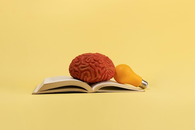 Um cérebro, uma lâmpada e livros sobre ideias de conceito criativo de fundo amarelo