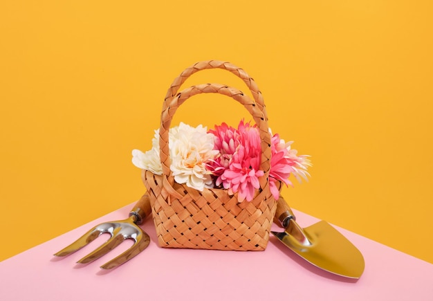 Um cesto decorativo de vime com flores frescas de primavera e ferramentas de jardim