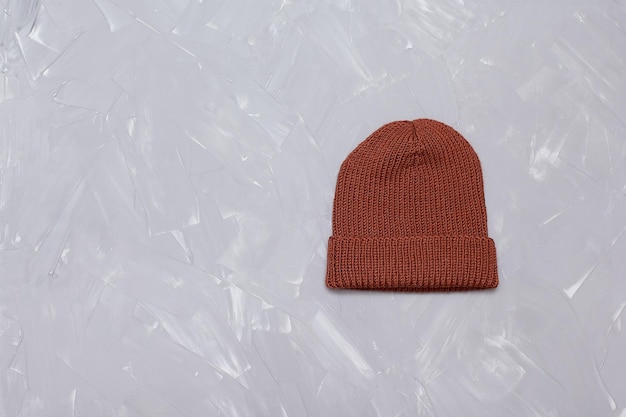 Um chapéu de lã tricotado feito de fio marrom está sobre uma mesa cinza roupas quentes de inverno