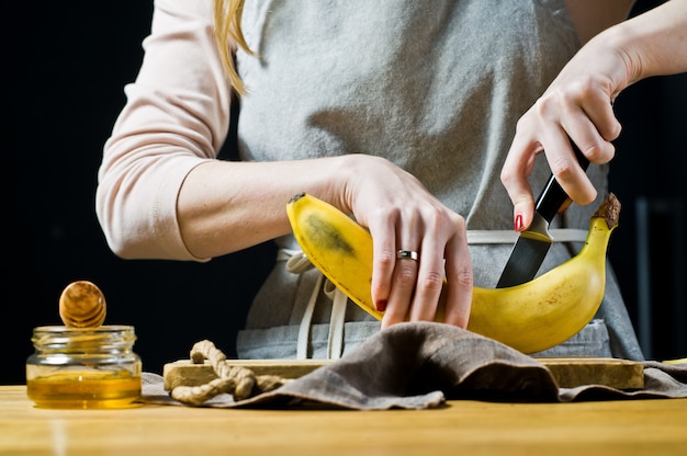 Um chef corta uma banana em fatias. Cozinhar bananas fritas.