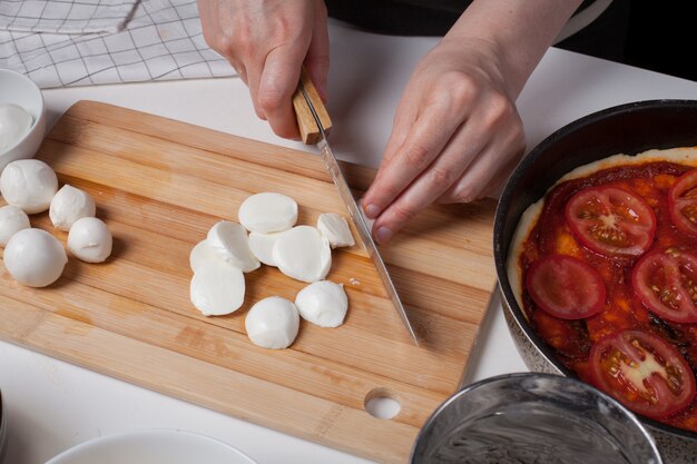 Um chef de mulher corta queijo mussarela.