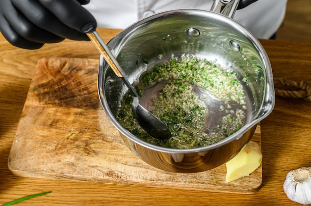 Um chef em luvas pretas prepara legumes salteados.