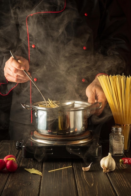 Um chef profissional prepara sopa de espaguete em uma panela na cozinha