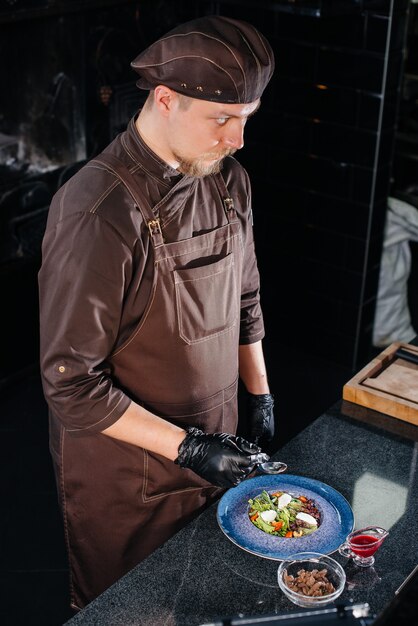 Um chef profissional prepara uma deliciosa salada fresca de vegetais verdes e vitela suculenta em um restaurante moderno e elegante. cozinhando em um restaurante.