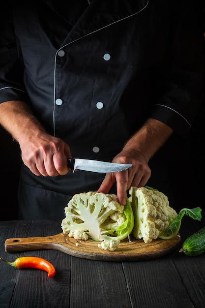 Um chef profissional se prepara para cortar uma couve-flor na cozinha de um restaurante