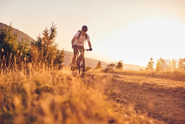 Um ciclista anda de bicicleta em estradas florestais ao pôr do sol