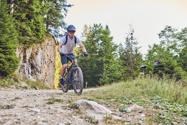 Um ciclista anda de bicicleta em estradas florestais extremas e perigosas Foco seletivo