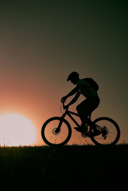 Um ciclista andando de bicicleta em uma montanha ao pôr do sol