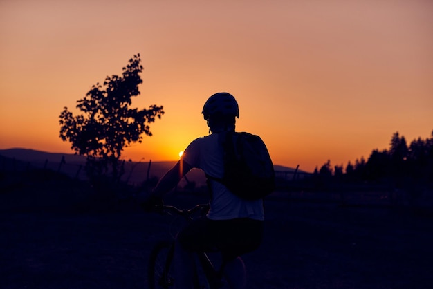 Um ciclista andando de bicicleta em uma montanha ao pôr do sol