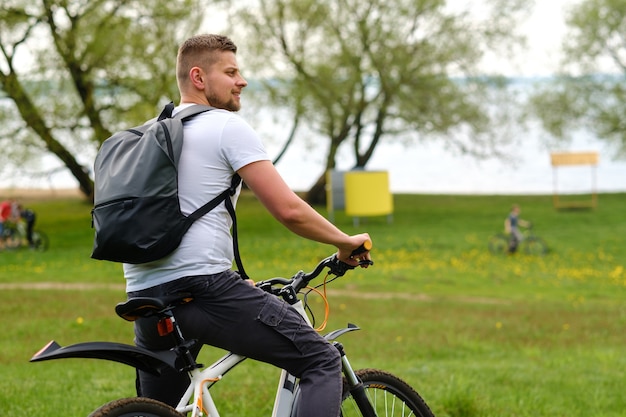 Um ciclista com uma mochila está em uma bicicleta em uma clareira curtindo a natureza.