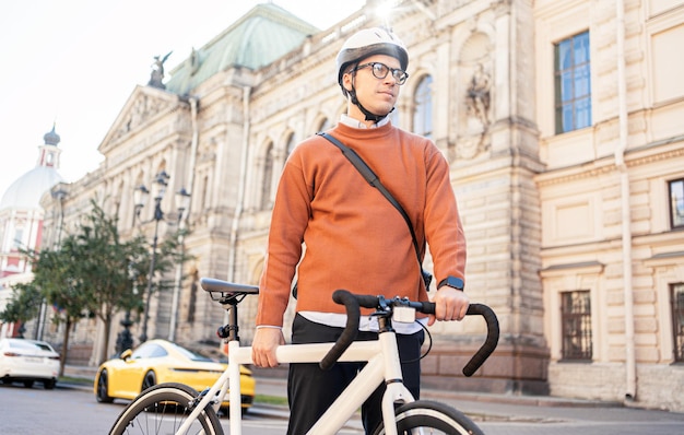 Um ciclista masculino em um capacete vai trabalhar com uma maleta Urban ecotransport Fitness watch na mão