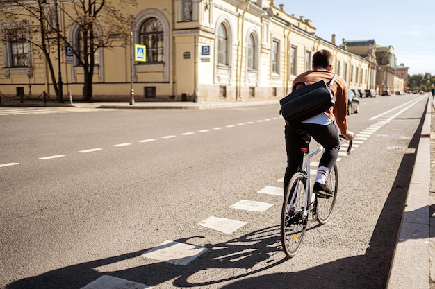 Um ciclista masculino vai trabalhar com uma maleta de bicicleta na cidade Transporte ecológico