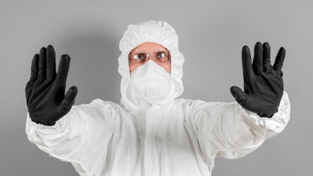 Foto um cientista médico ou policial usa roupas de proteção e mostra um sinal de pare. o conceito de saúde e crime.