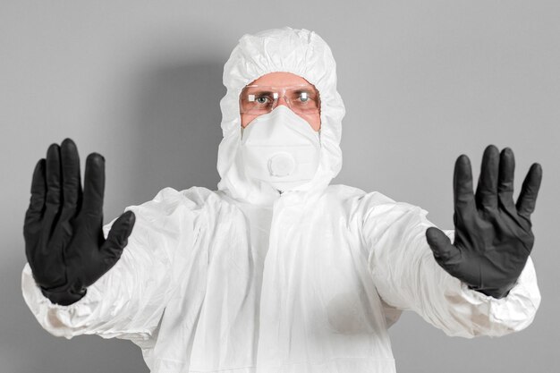 Um cientista médico ou policial usa roupas de proteção e mostra um sinal de pare