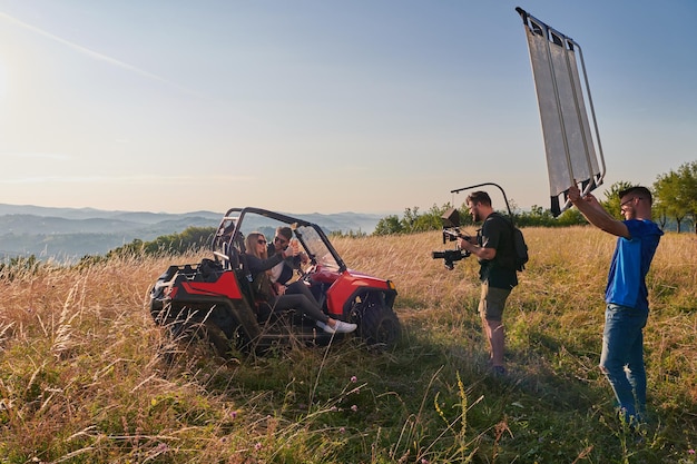 um cinegrafista equipado profissionalmente gravando um jovem casal desfrutando de um passeio de buggy montanha acima