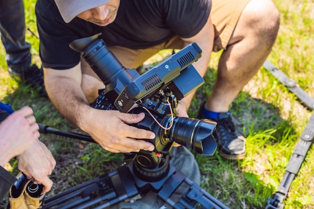 Um cinegrafista profissional prepara uma câmera e um tripé antes de fotografar.