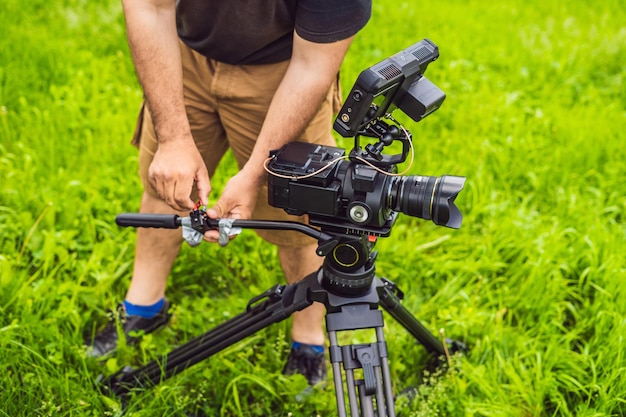 Um cinegrafista profissional prepara uma câmera e um tripé antes de fotografar.